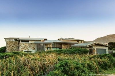 On the southern side, protective stone walls provide a solid base for the fractured, wind-cropped roofs, all nestled in the coastal thicket.